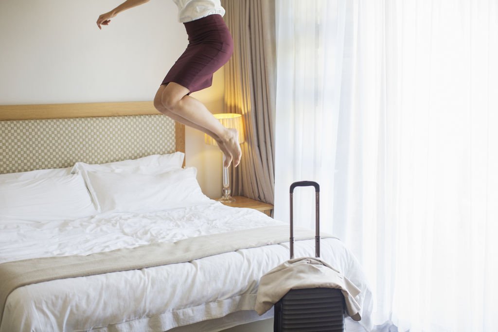 Businesswoman Jumpin on Bed in Hotel Room