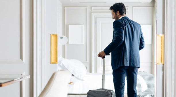 Businessman with wheeled luggage in suite