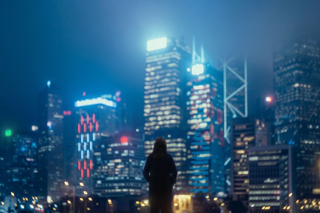 Young confident woman standing against urban cityscape and looking away