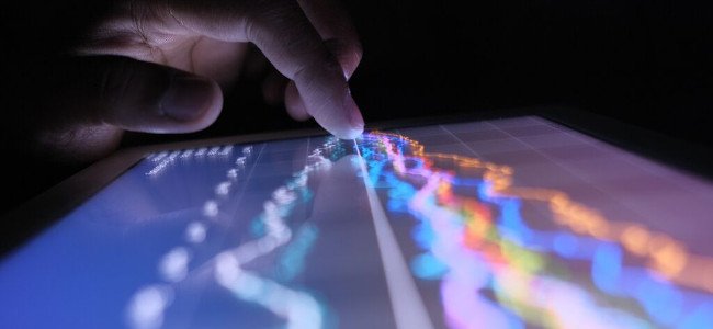 A man hand with digital tablet analyzing stock market graph at night