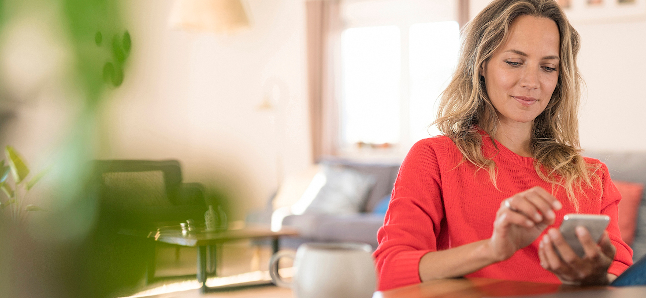 Woman using cell phone on dining table at home