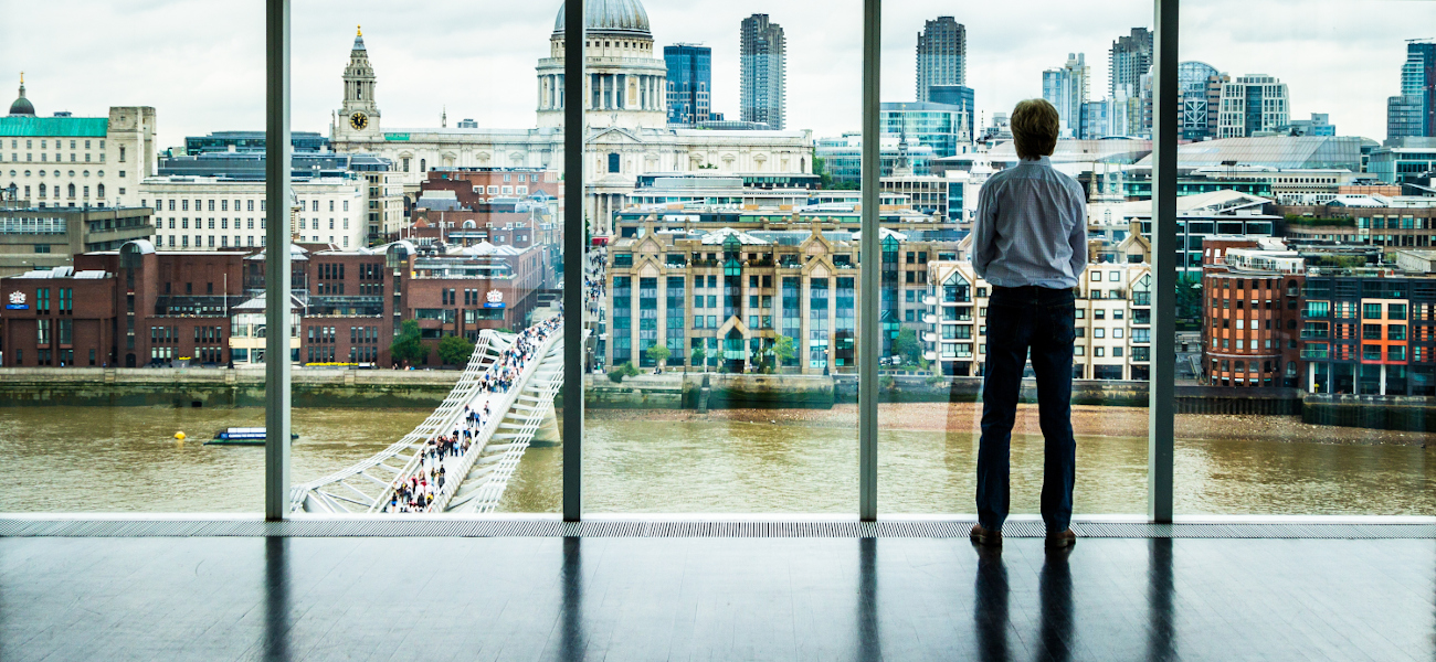 Businessman looks at the London Skyline from his Office Window