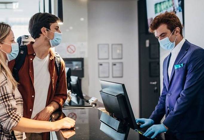 Couple wearing protective face mask while doing check-in at the hotel reception (2)