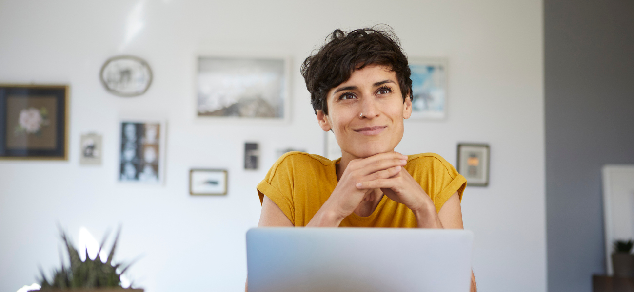 Portrait of smiling woman at home sitting at table using laptop