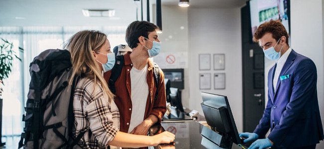 Couple wearing protective face mask while doing check-in at the hotel reception