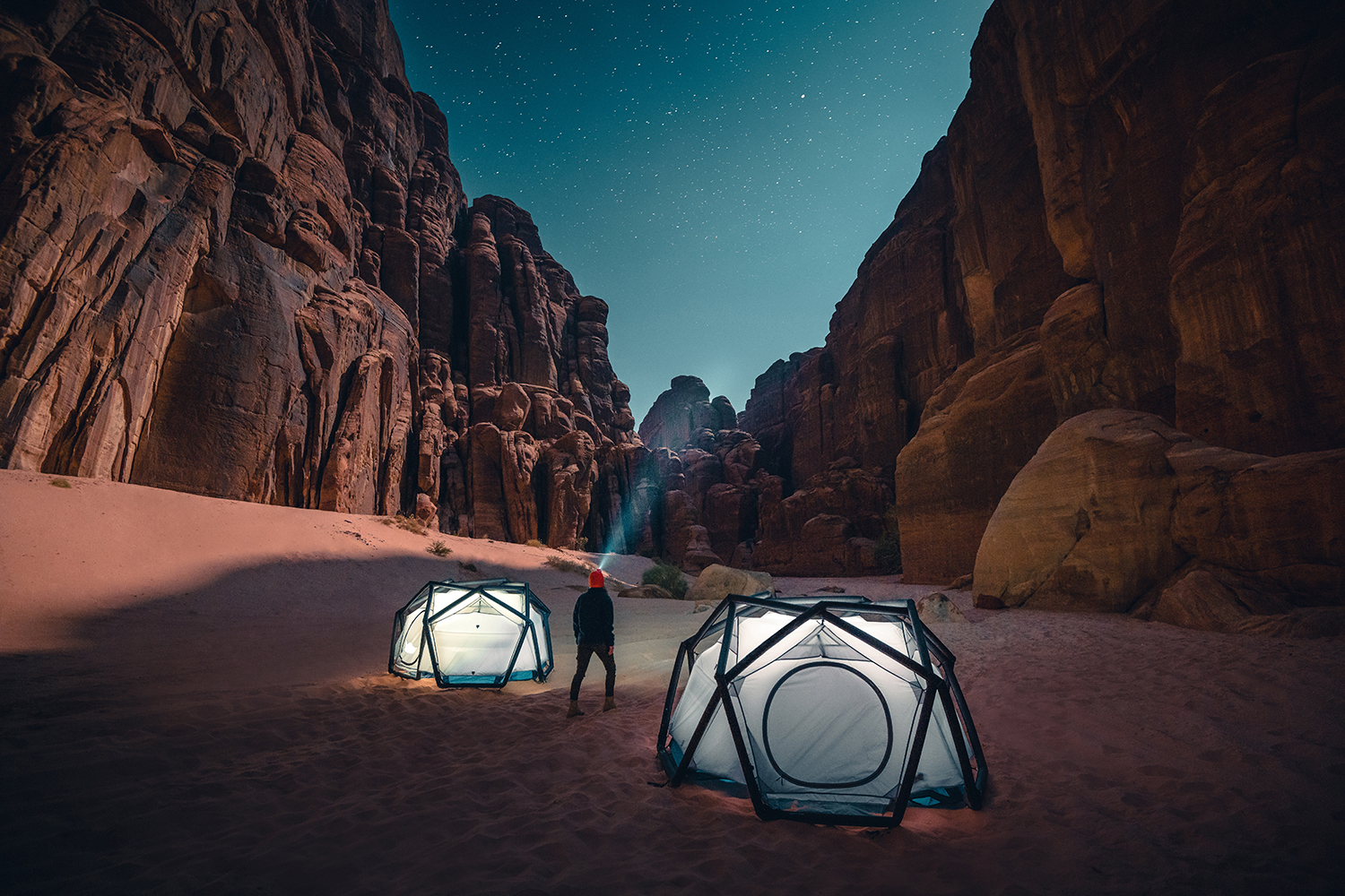 a man standing next to a tent in the desert