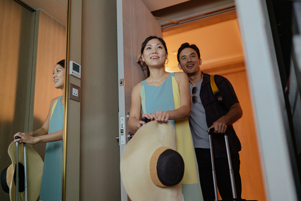 Happy Asian couple making their way from the hotel corridor to their room