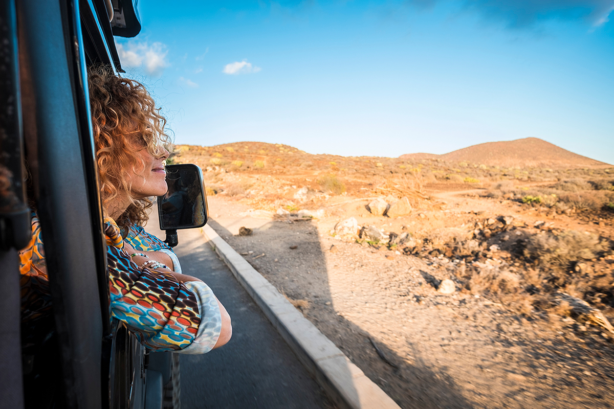 beautiful caucasian young woman traveling with an off road black car and looking outside the landscape. desert and mountains travel scenic place for nice lady enjoyed and smiled, scenery valley