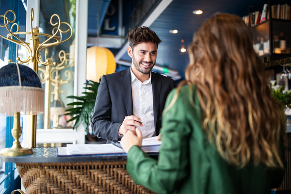 Hotel receptionist assisting guest for checking in Male hotel receptionist helping a woman guest in checking in process. Woman in hotel check-in at reception talking with the concierge at front office
