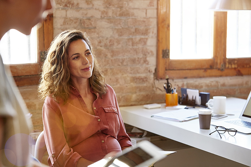 Pregnant businesswoman looking away at desk Pregnant businesswoman looking away at desk. She is wearing shirt at workplace.