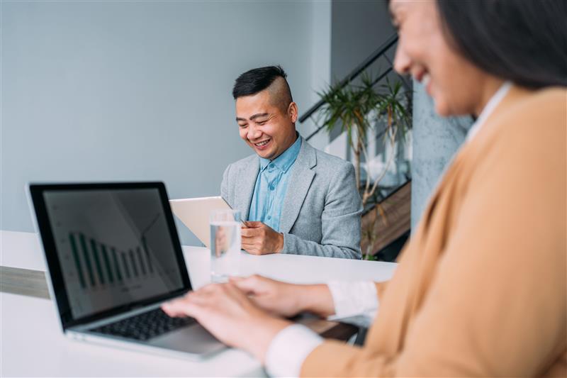 a man and woman looking at a laptop